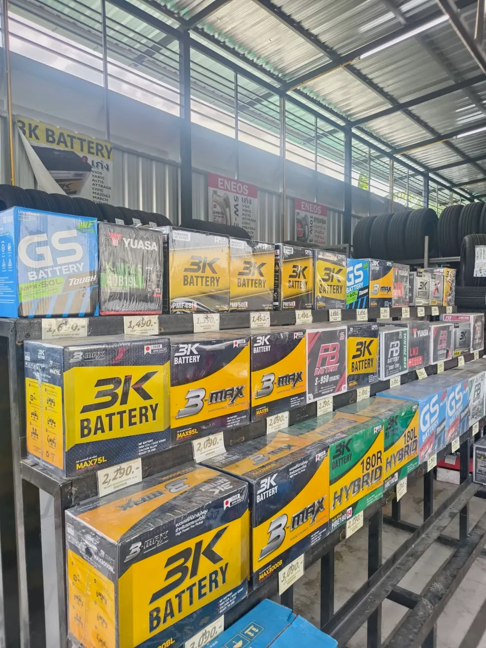 แบตเตอรี่รถยนต์หลายยี่ห้อวางเรียงในร้าน ทั้ง 3K GS FB และ Yuasa พร้อมป้ายราคา